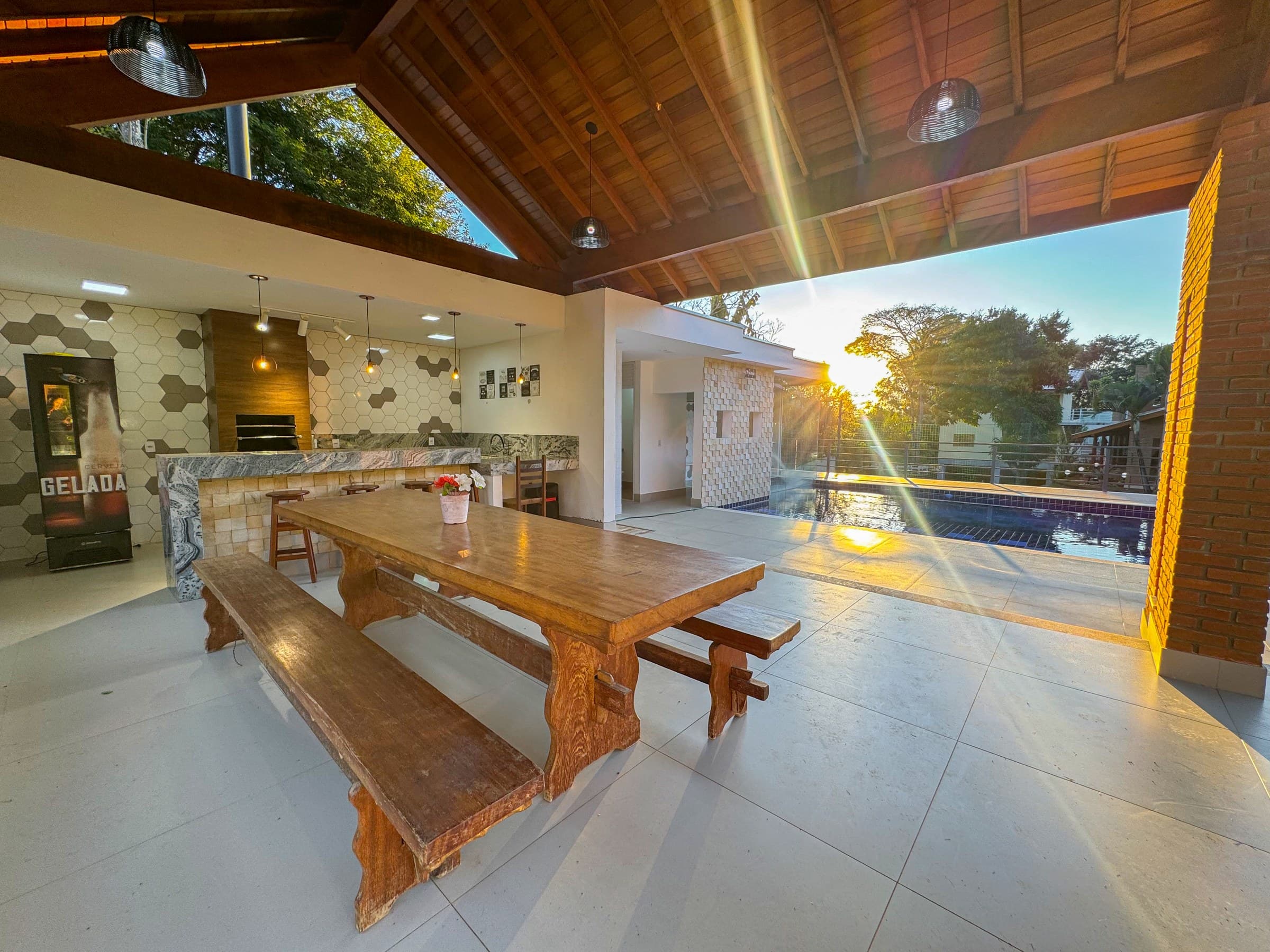 A Área Gourmet Integrada à Piscina foi projetada para reunir lazer, gastronomia e convivência em um único ambiente. Com churrasqueira, bancada de preparo, ampla mesa de madeira e integração direta com a piscina, hidromassagem, sauna e cascata, é o espaço ideal para confraternizações, almoços, churrascos e celebrações ao ar livre. Um ambiente elegante, funcional e totalmente integrado ao paisagismo da Chácara Beija-Flor.3